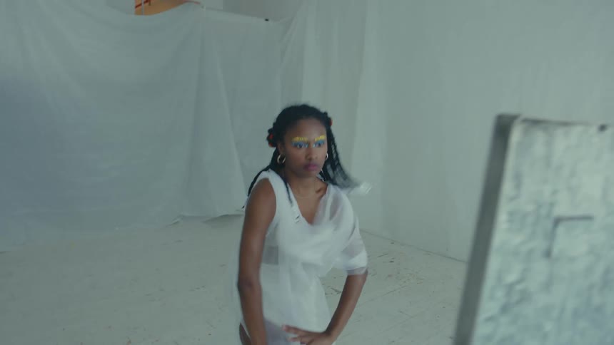 Woman wearing a white toga dances inside a roomsurrounded by mirrors