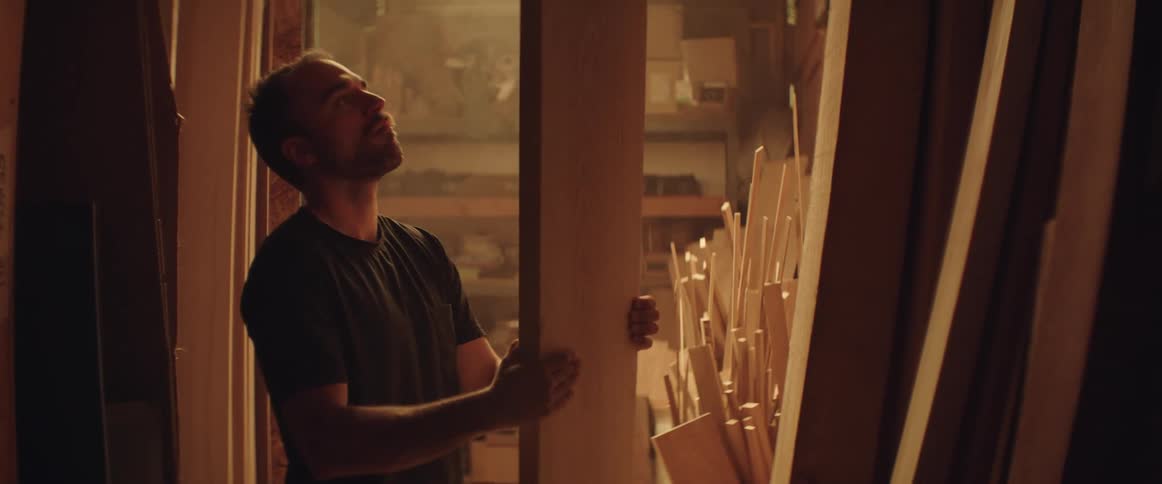 Carpenter examines a board while standing in workshop
