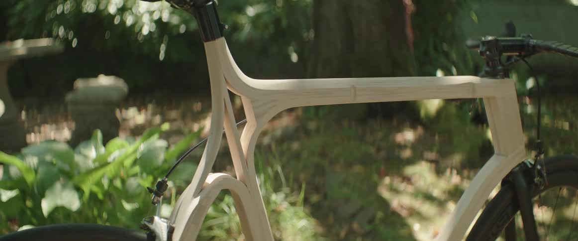 Wooden bicycle parked outdoors near a tree