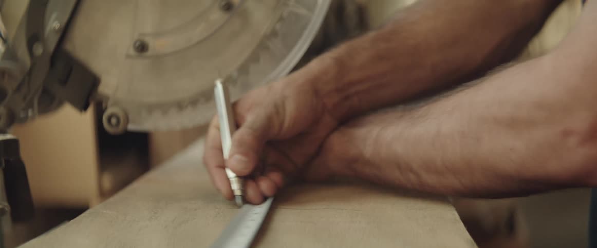 Close up of a carpenter marking a plank with a pencil using a tape measure