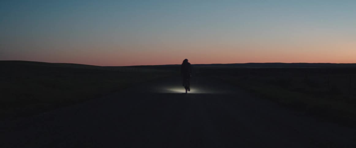 A bicycle rider with flashing taillight traveling on an empty road at dusk