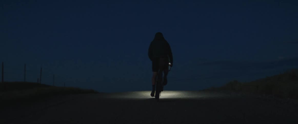 A cyclist seen on a rural road at night