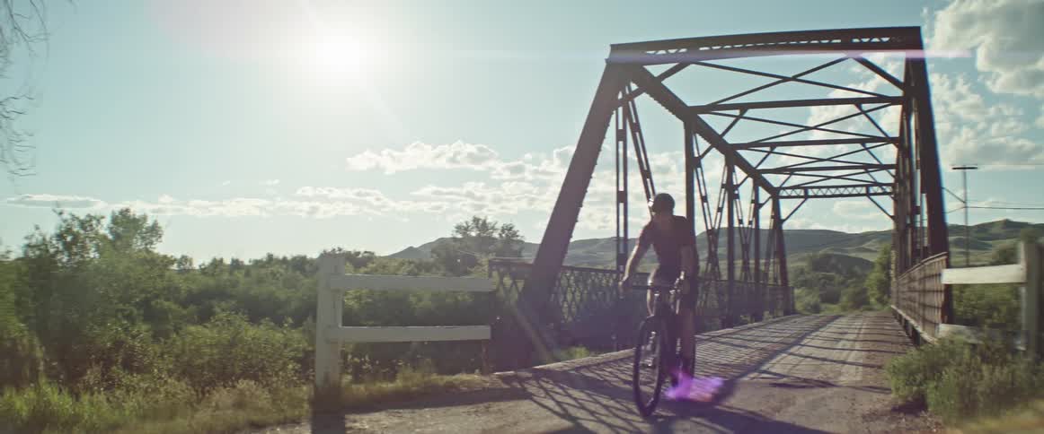 A man bikes across a bridge
