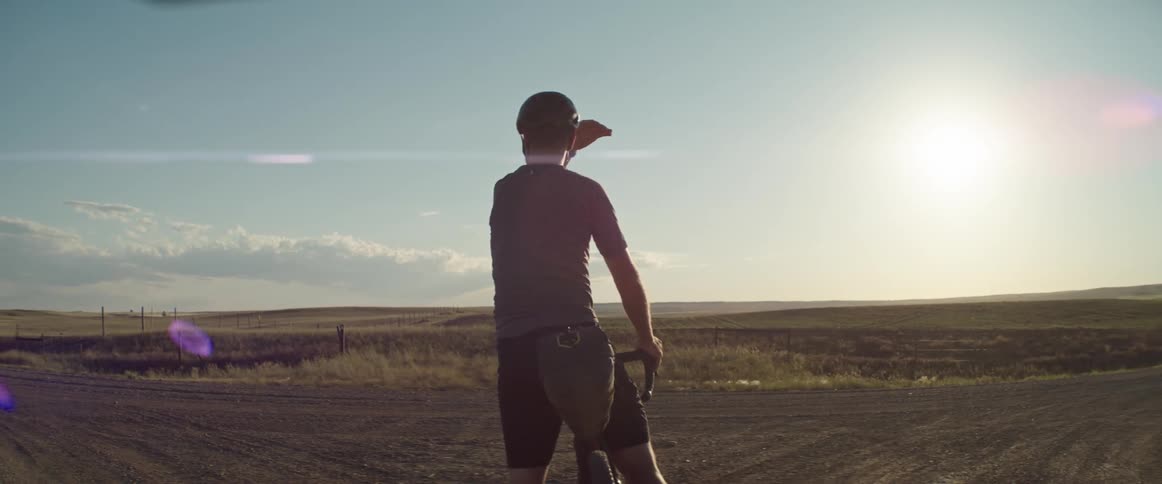 A man wearing a helmet stops his bicycle confused about which direction to take