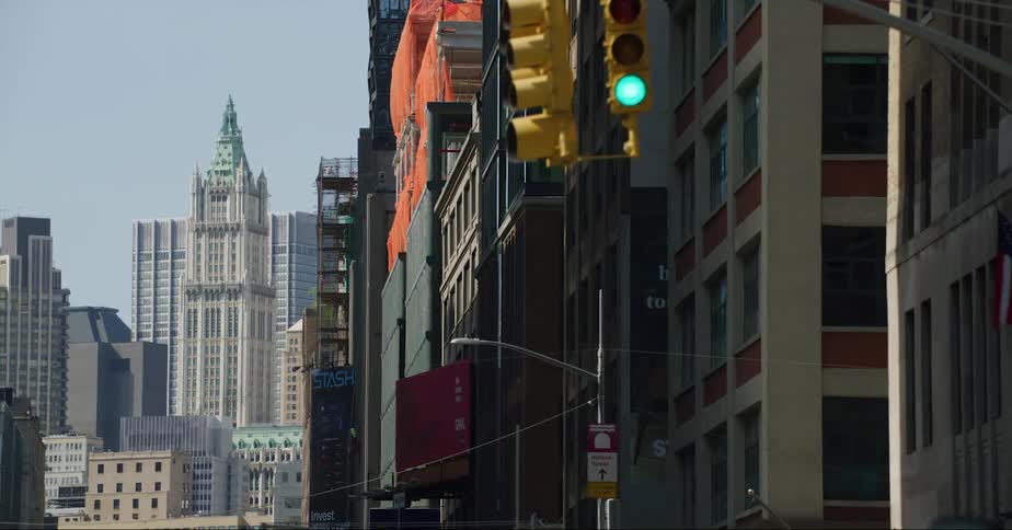 Vehicles drive down a city street surrounded by tall buildings