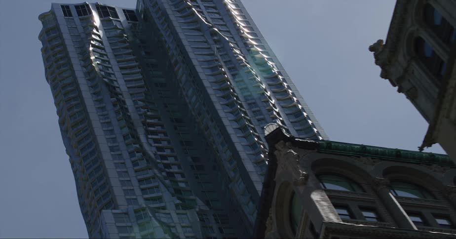 The sun shines upon a tall shiny skyscraper with a twisting design standing high in a clear sky