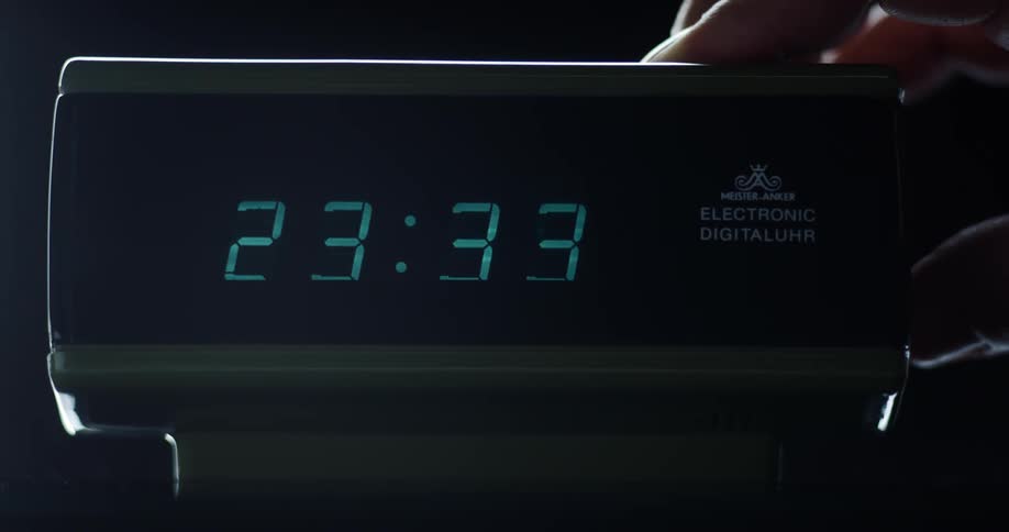 A person sets their electronic alarm clock