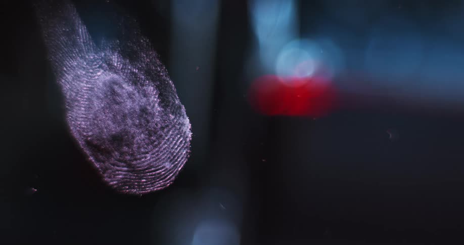 Lens with fingerprint pans over dark scene lit by flashing blue and red lights