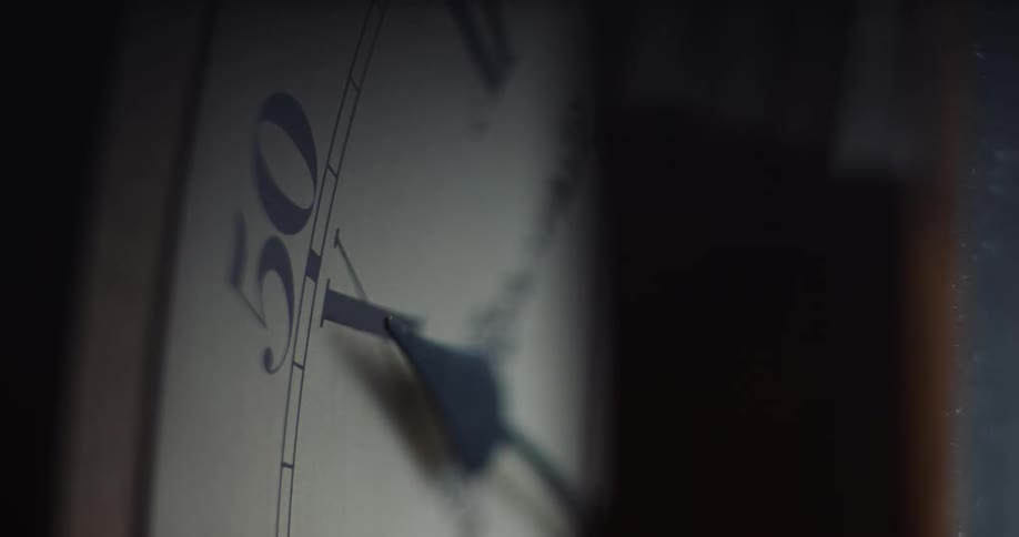 Arm of an antique analog clock stuck over the dial inside a dimly lit room