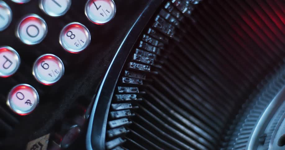 Red light glows softly on the keys and typebars of a manual typewriter