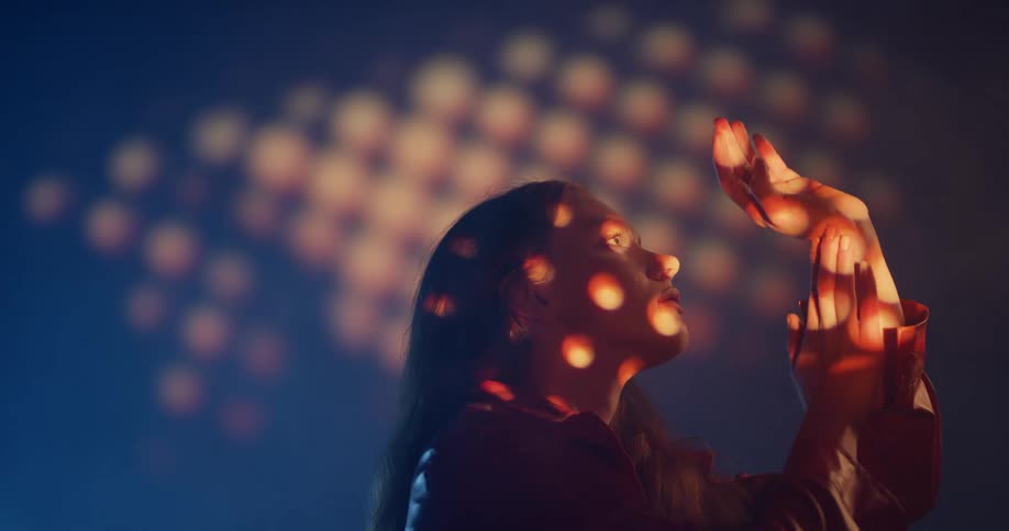 Woman dances in front of wall under a soft spotlight