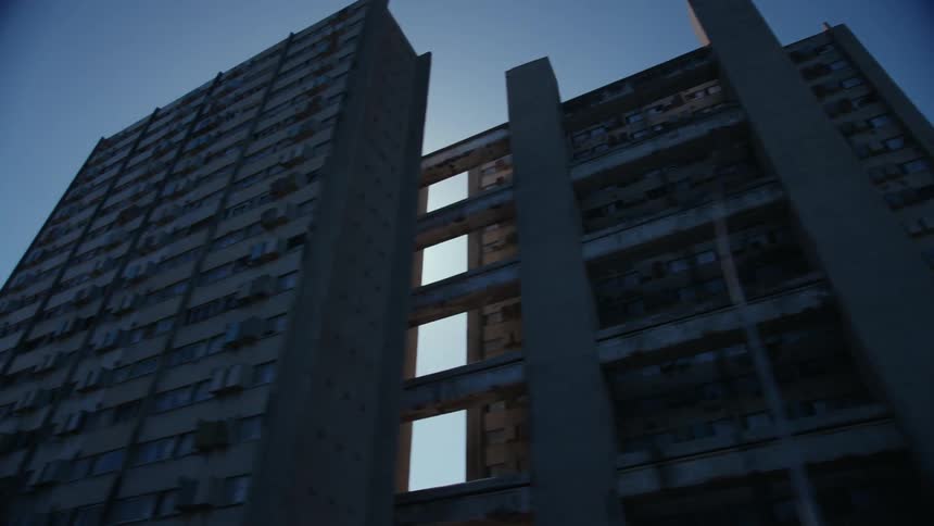 Moving through a neighborhood and looking up at tall apartment buildings as the sun shines between buildings