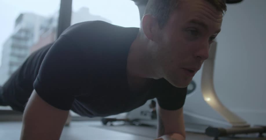 Man lying on the floor face down while suspended on his elbows while exercising