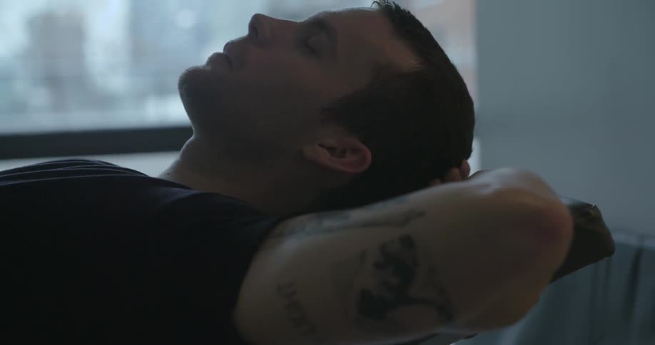 A man lays and rests in front of a window