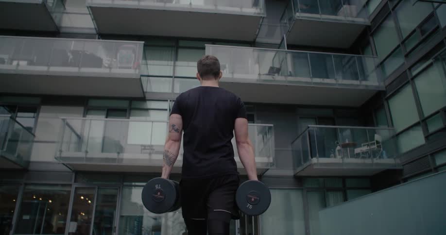 Athlete carrying heavyweights  towards a building