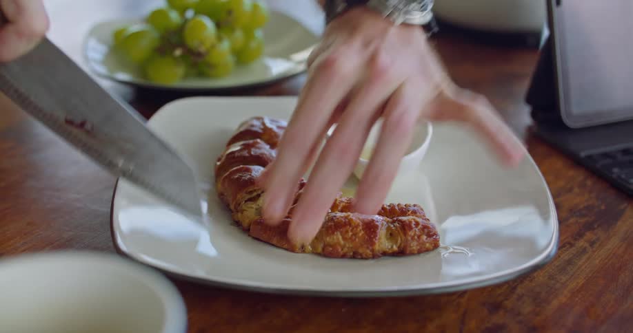 Man plates pastry on plate set next to computer