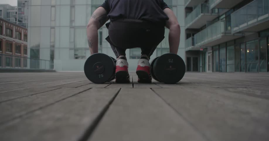 A man lifts some weights and carries them away
