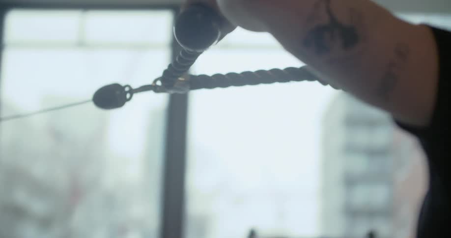 A man working out in a gym with big windows
