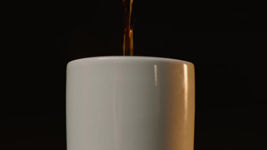 Coffee is poured into white cup in studio