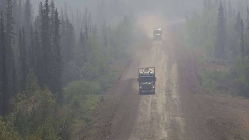 Trucks driving down a dirt road