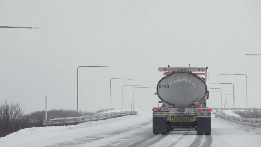 A truck drives down a snowy road