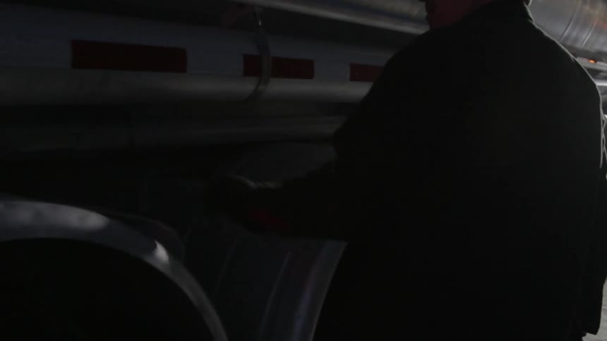 A man checks the tires of a semi-truck