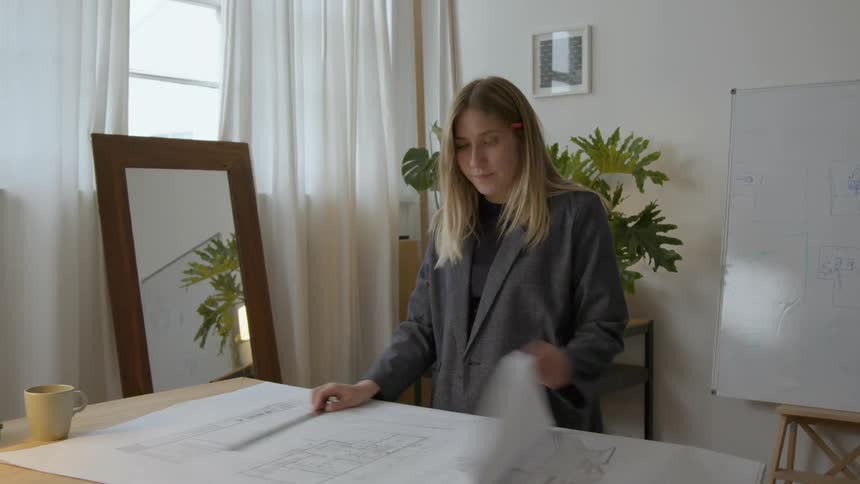 A woman is flipping through blueprints