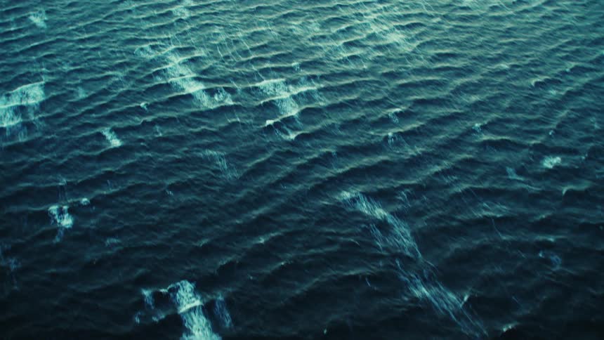 The sun shines on ripples in the water as waves roll across the ocean