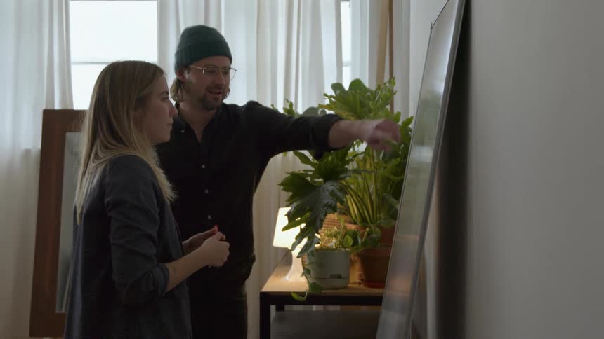 A man and woman discuss information written on a whiteboard