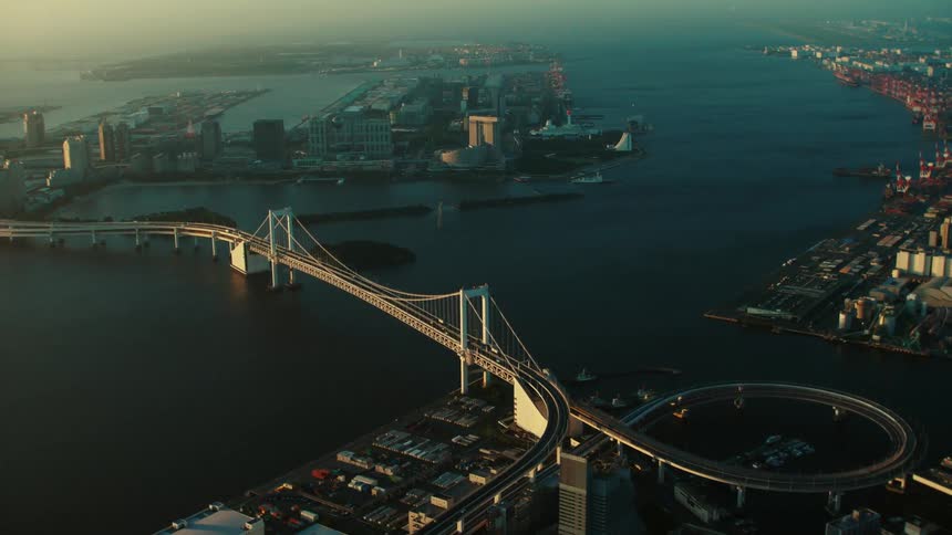 An aerial view of cars driving across a bridge and a city on the shore