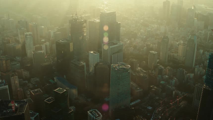 An aerial view of sunlight shining over skyscrapers and buildings in a large city