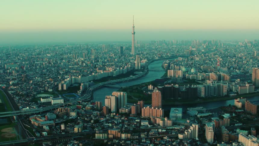 An aerial view of a river flowing through a large city at sunrise