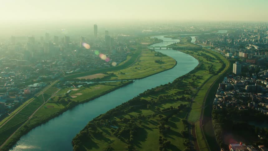 Aerial view of river and bridges next to city with high rise buildings and apartment buildings at dawn