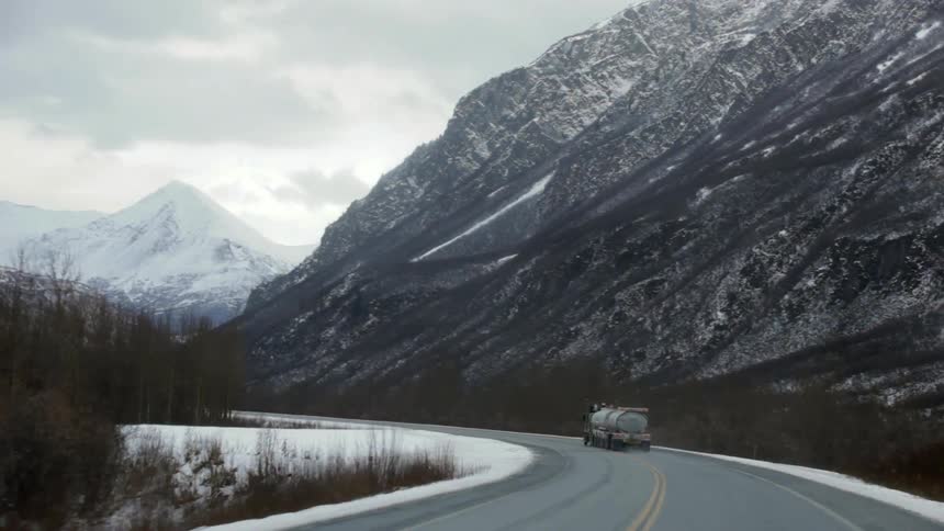 A truck drives down a snowy road