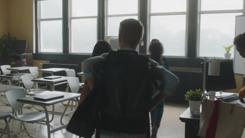 Teacher and students entering a classroom and getting settled