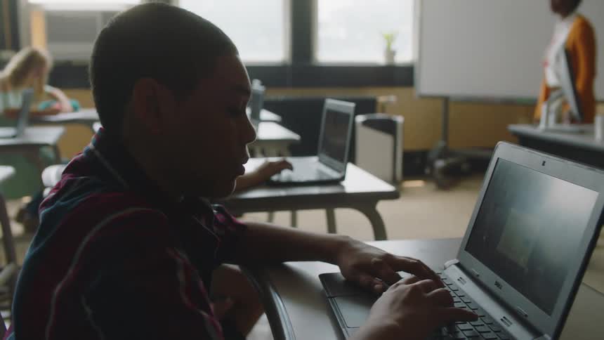 Students work on laptops in a classroom