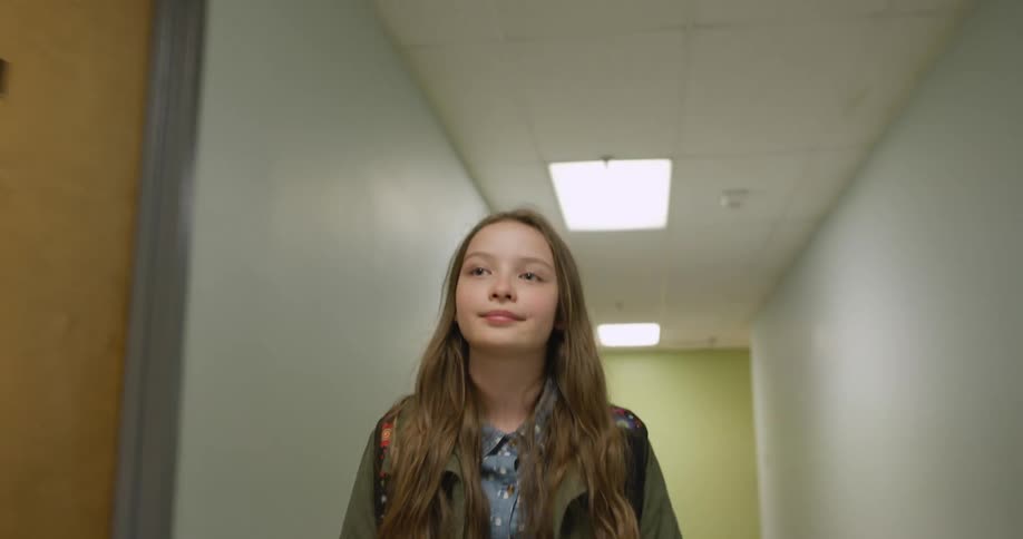 A young girl walks down a school hallway