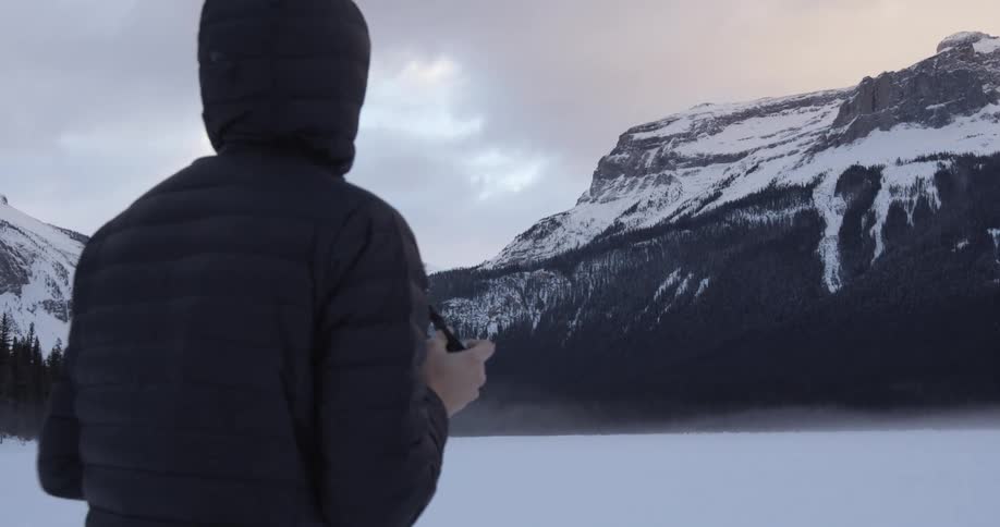 A man eats something as he looks at a mountain
