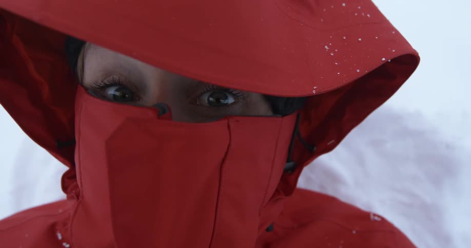 A woman is lying in snow wearing a large red coat