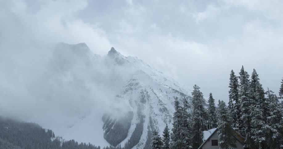 A snow covered mountain is covered with clouds