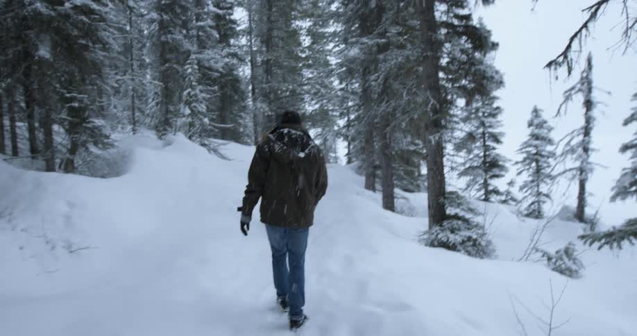 Two men are hiking as it snows uphill