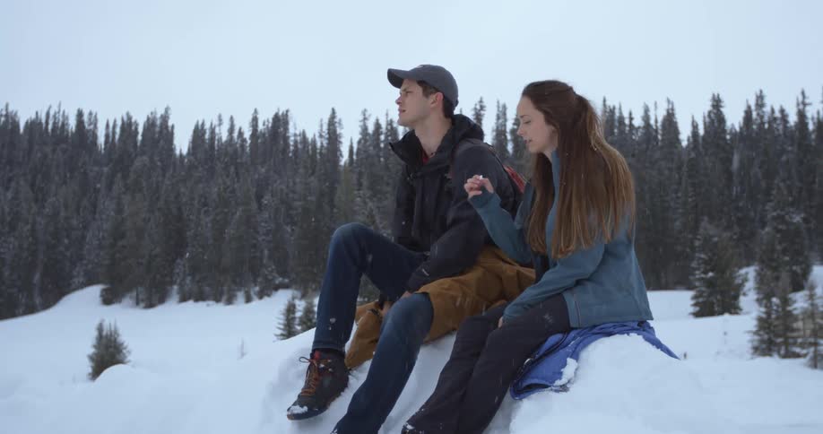 Two women throw snowballs at each other in a snow-covered landscape during the day