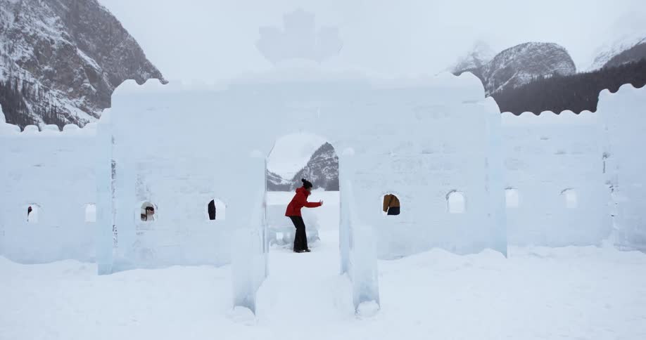 People walk behind a large ice wall