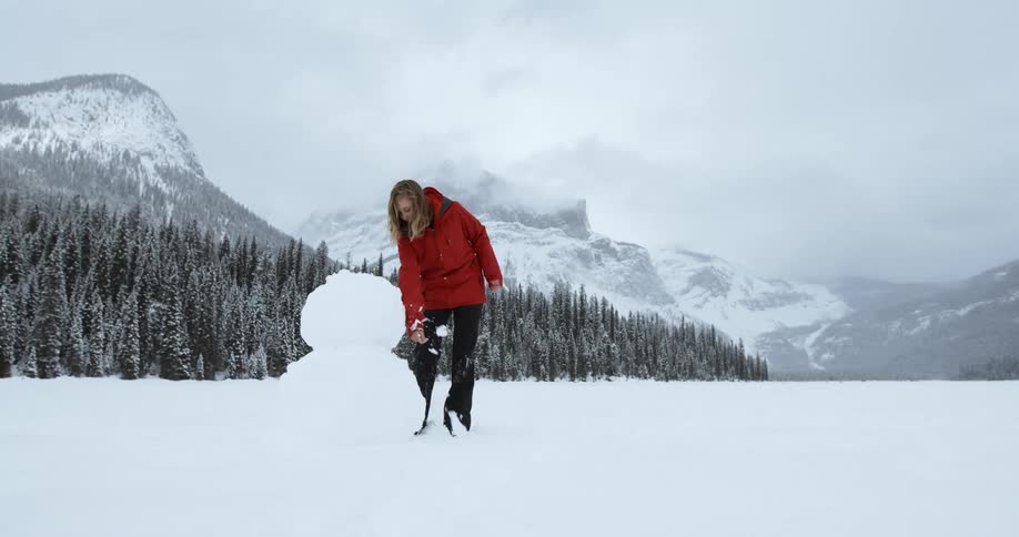 Woman forming a snowman in the vast wilderness