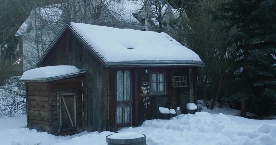 A small cabin has snow all around it