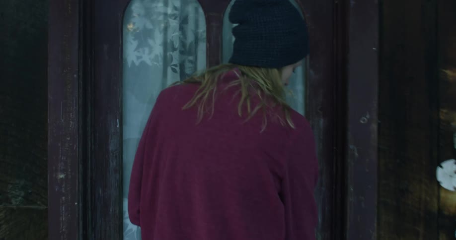 A woman walks towards her home and enters