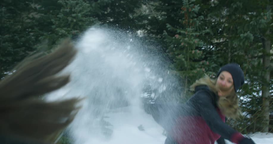 A woman throws a snowball at her friend