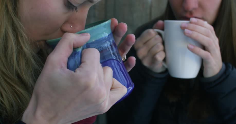 Two women drink from a mug together