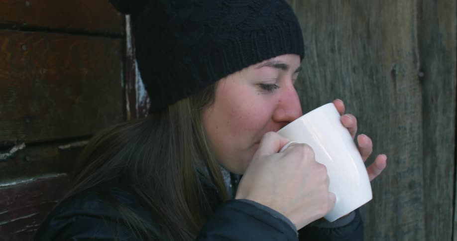 A woman takes a drink from a mug