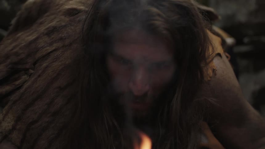 A man bends over a fire on the ground